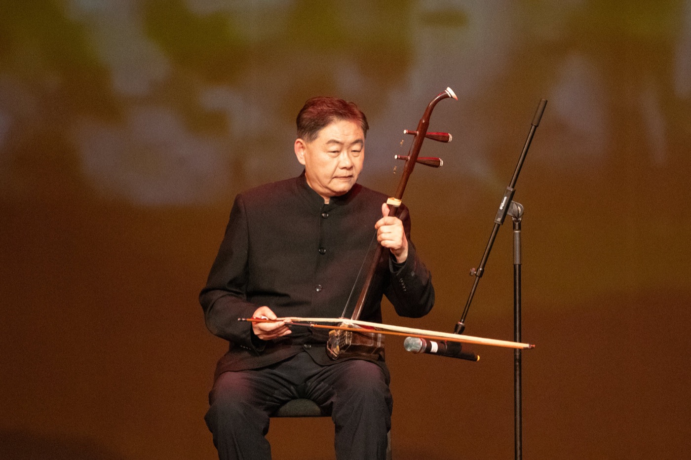 An erhu musician performs beneath warm stage lights