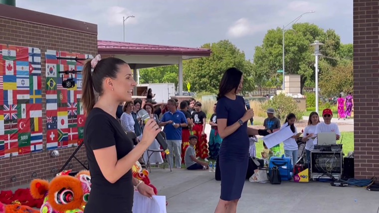 Community hosts welcome neighbors beside international flags