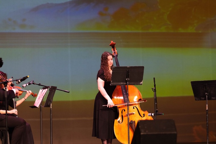 A cellist performs before a projected landscape
