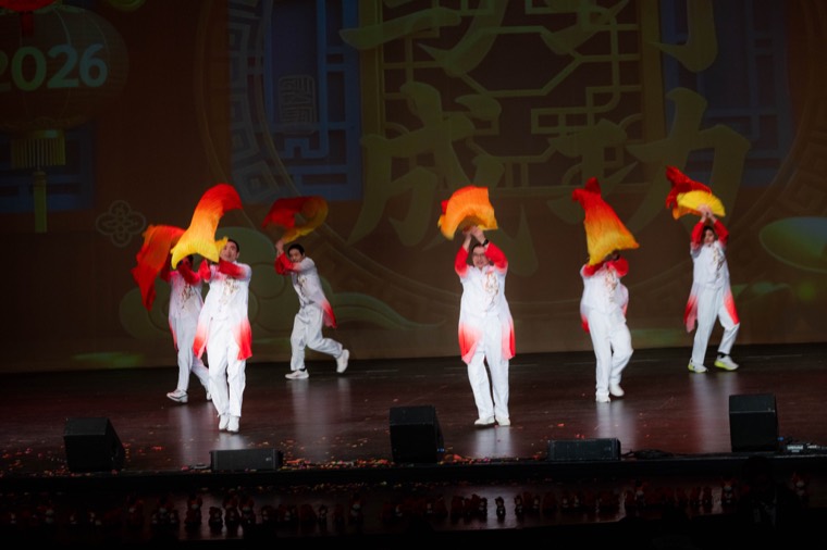 Dancers move red and yellow fans across the stage