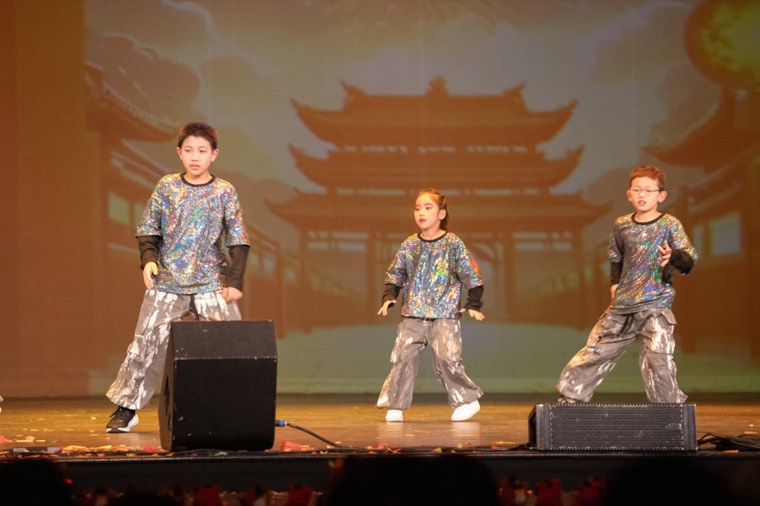Three young dancers perform in silver costumes