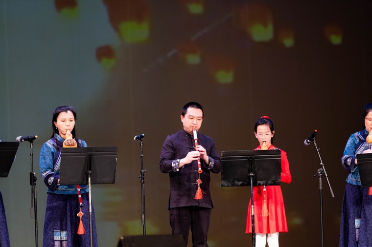 Three musicians perform Chinese wind instruments onstage