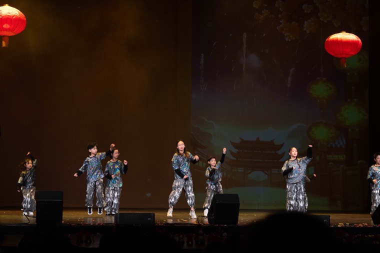 Young performers share a coordinated dance beneath red lanterns