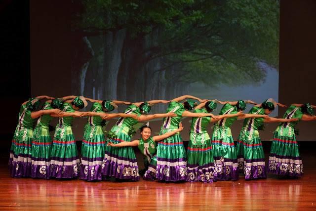 A group of dancers in green and purple costumes performing in formation
